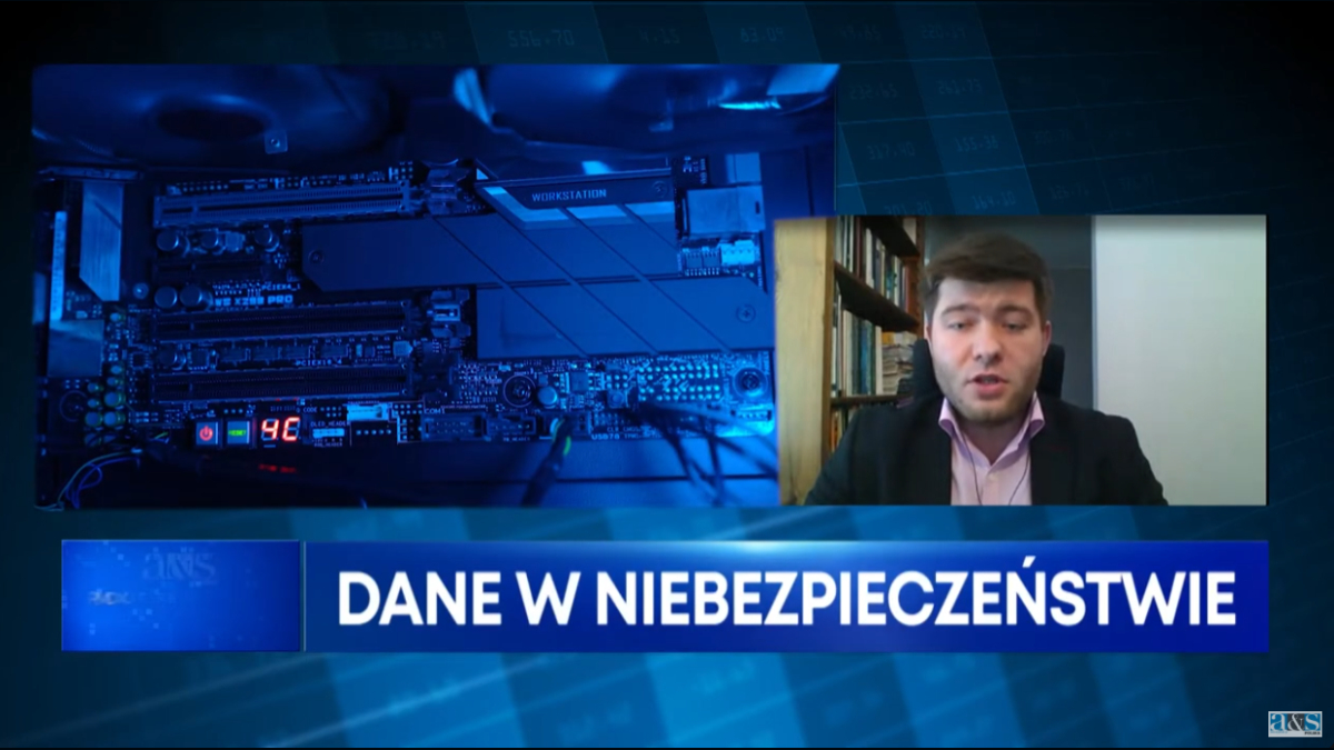 Po prawo okienko z udzielającym wywiadu mężczyzną w garniturze. Za nim widać półkę z książkami. Na dole niebieski pasek z białym napisem: Dane w niebezpieczeństwie. W tle zbliżenie na sprzęt telewizyjny, utrzymane w niebieskiej kolorystyce. W prawym dolnym rogu logo a&s.